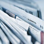 A close-up of a stack of newspapers, with the headline World Business visible, suggesting global business news—perhaps even features on innovations like golf simulators or trends in golf sim technology. The edges of the papers are slightly rumpled.